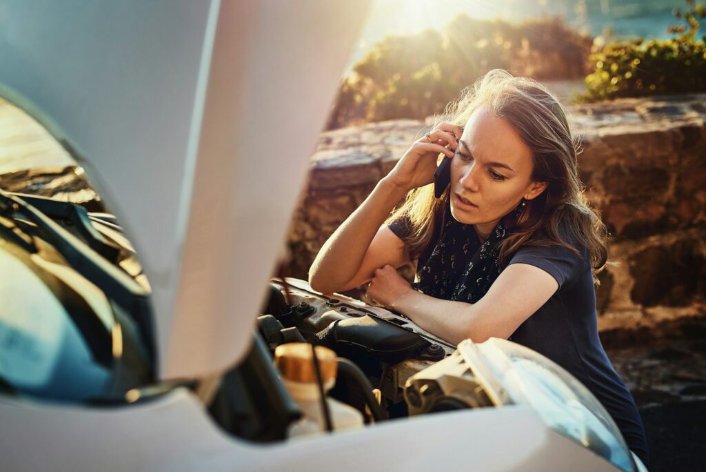 Cropped shot of a young woman calling roadside assistance after breaking down